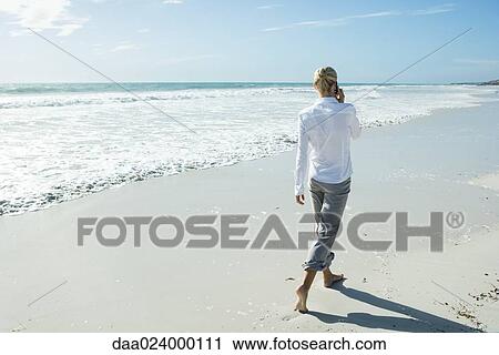 Woman walking barefoot on beach, using cell phone, rear view View Large Photo Image Stock Image - Woman walking barefoot on beach, using cell phone, rear view. Fotosearch