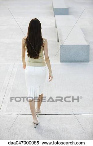 Woman walking in city square, rear view View Large Photo Image Stock Photography - Woman walking in city square, rear view. Fotosearch