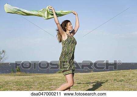 Woman walking in wind, holding up shawl in the air, full length View Large Photo Image Stock Image - Woman walking in wind, holding up shawl in the air, full length. Fotosearch