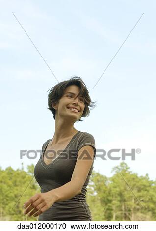 Woman walking outdoors, smiling, trees in background View Large Photo Image Stock Image - Woman walking outdoors, smiling, trees in background. Fotosearch