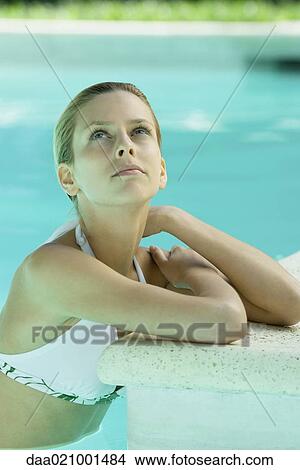 Picture - Woman wearing halter bathing suit, head and shoulders, leaning on edge of pool. Fotosearch