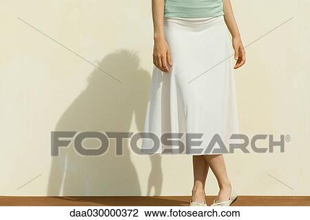 Woman wearing skirt, legs crossed at ankle, cropped view View Large Photo Image Stock Image - Woman wearing skirt, legs crossed at ankle, cropped view. Fotosearch