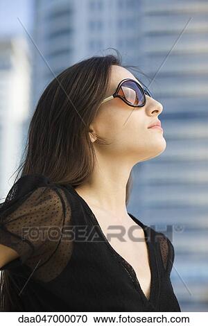 Woman wearing sunglasses, looking up, portrait View Large Photo Image Stock Image - Woman wearing sunglasses, looking up, portrait. Fotosearch