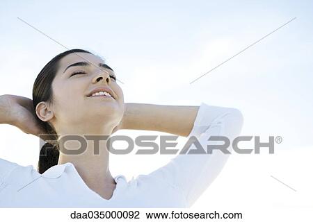 Woman with eyes closed, hands behind head View Large Photo Image Stock Image - Woman with eyes closed, hands behind head. Fotosearch