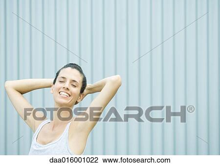 Woman with hands behind head, eyes closed View Large Photo Image Stock Image - Woman with hands behind head, eyes closed. Fotosearch