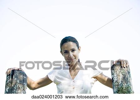 Woman with hands on wooden posts, smiling at camera, low angle view View Large Photo Image Stock Image - Woman with hands on wooden posts, smiling at camera, low angle view. Fotosearch