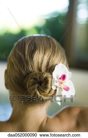 Stock Image - Woman with orchid in hair, rear view. Fotosearch