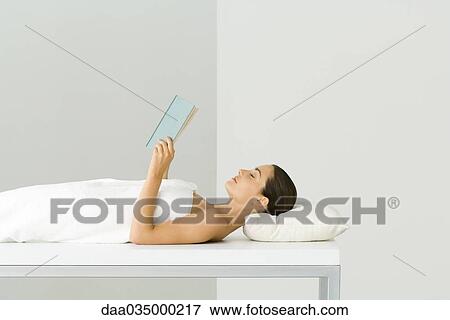 Woman wrapped in towel, lying on massage table, holding book, eyes closed View Large Photo Image Stock Photo - Woman wrapped in towel, lying on massage table, holding book, eyes closed. Fotosearch