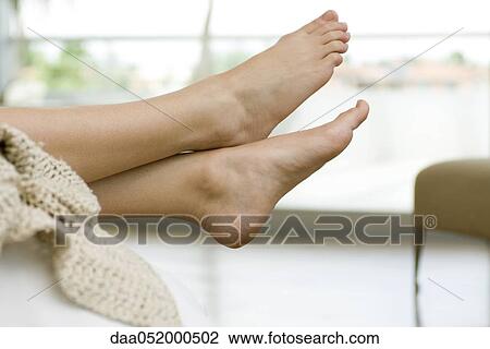 Stock Image - Woman's bare feet, legs crossed at ankle. Fotosearch