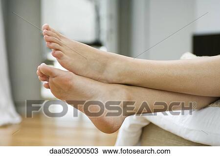 Stock Image - Woman's bare feet, legs crossed at ankle. Fotosearch