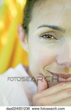 Stock Photograph - Woman's face and hand, looking at camera, close-up, cropped. Fotosearch