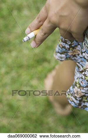 Stock Image - Woman's hand holding cigarette, cropped. Fotosearch
