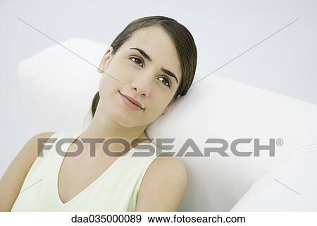Stock Photo - Women leaning against armrest smiling and looking away. Fotosearch