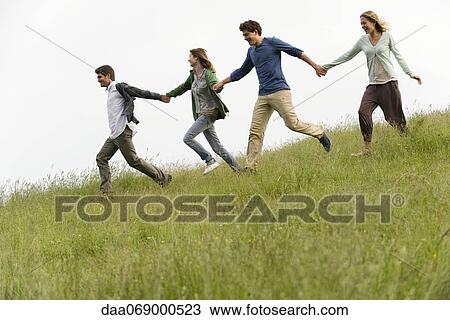 Young adults running on meadow holding hands View Large Photo Image Stock Image - Young adults running on meadow holding hands. Fotosearch