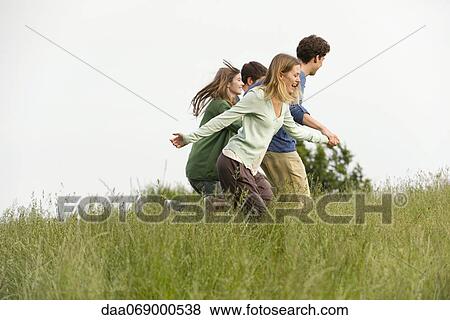 Stock Photo - Young adults running on meadow. Fotosearch