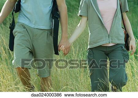 Stock Photograph - Young couple hiking through field, cropped. Fotosearch