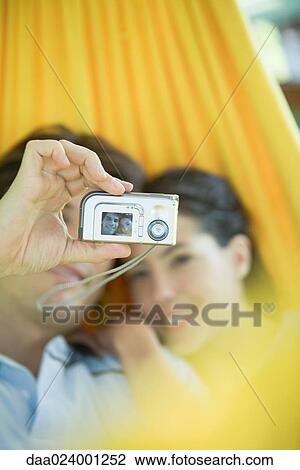 Young couple lying in hammock, taking photo of selves with digital camera View Large Photo Image Stock Image - Young couple lying in hammock, taking photo of selves with digital camera. Fotosearch
