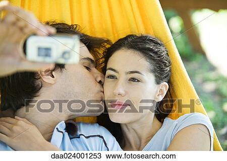 Young couple lying in hammock, taking photo of selves with digital camera View Large Photo Image Stock Image - Young couple lying in hammock, taking photo of selves with digital camera. Fotosearch