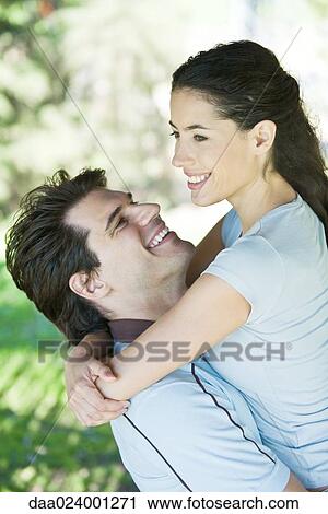 Stock Image - Young couple, man holding woman, waist up. Fotosearch