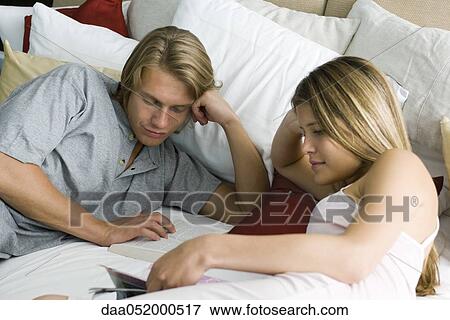 Stock Photo - Young couple reading together in bed. Fotosearch