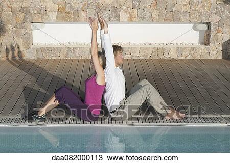 Young couple sitting back to back at poolside, arms raised View Large Photo Image Stock Image - Young couple sitting back to back at poolside, arms raised. Fotosearch