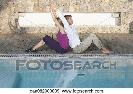 Young couple sitting back to back at poolside stretching View Large Photo Image Stock Photo - Young couple sitting back to back at poolside stretching. Fotosearch