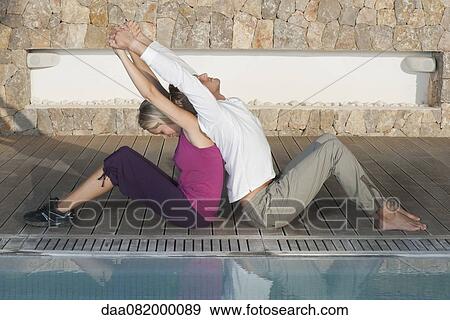 Young couple sitting back to back at poolside stretching View Large Photo Image Stock Photo - Young couple sitting back to back at poolside stretching. Fotosearch