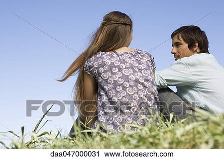 Young couple sitting on grass having conversation View Large Photo Image Stock Image - Young couple sitting on grass having conversation. Fotosearch