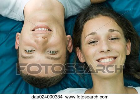 Picture - Young couple smiling at camera, man upside down, close-up. Fotosearch