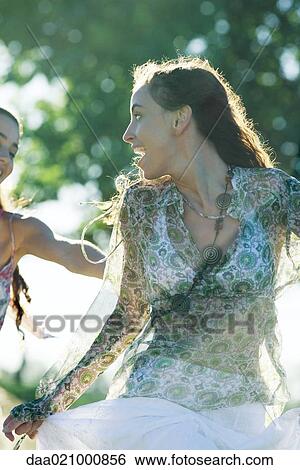 Young female friends outdoors, one looking over shoulder at the other View Large Photo Image Stock Photograph - Young female friends outdoors, one looking over shoulder at the other. Fotosearch