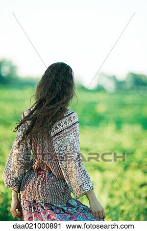 Stock Image - Young hippie woman standing outdoors, rear view. Fotosearch