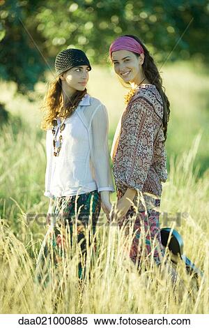 Young hippie women standing in field, one holding guitar and smiling at camera View Large Photo Image Stock Photography - Young hippie women standing in field, one holding guitar and smiling at camera. Fotosearch