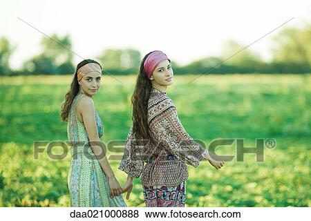Young hippie women walking through field, holding hands, looking over shoulders at camera View Large Photo Image Stock Photo - Young hippie women walking through field, holding hands, looking over shoulders at camera. Fotosearch