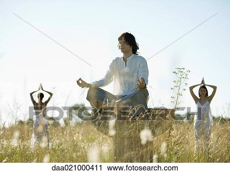 Young male and females doing yoga in field View Large Photo Image Stock Image - Young male and females doing yoga in field. Fotosearch