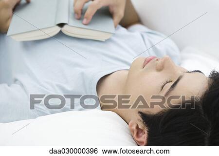 Young male lying on back with eyes closed, holding book on chest View Large Photo Image Stock Photograph - Young male lying on back with eyes closed, holding book on chest. Fotosearch