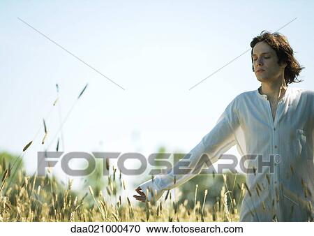 Young male standing in field, arm out, eyes shut View Large Photo Image Stock Image - Young male standing in field, arm out, eyes shut. Fotosearch