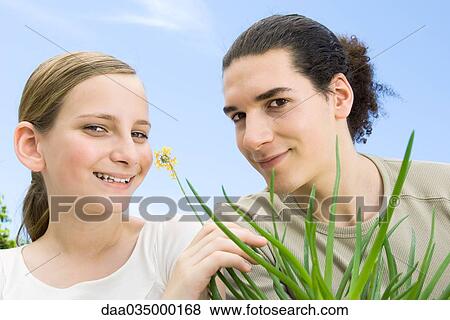 Stock Photo - Young man and preteen girl with flowering aloe plant, smiling at camera. Fotosearch