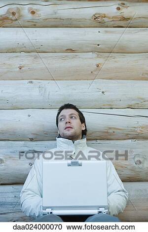 Young man dressed in winter clothing, using laptop View Large Photo Image Stock Image - Young man dressed in winter clothing, using laptop. Fotosearch