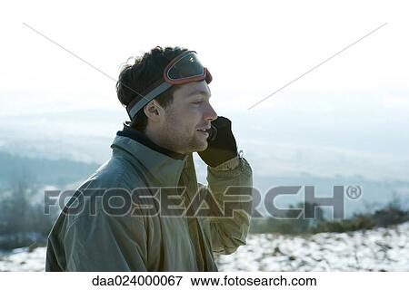 Young man dressed in winter clothing, using cell phone View Large Photo Image Stock Photo - Young man dressed in winter clothing, using cell phone. Fotosearch
