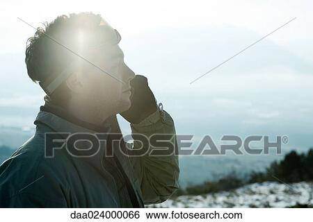 Young man dressed in winter clothing, using cell phone View Large Photo Image Stock Photograph - Young man dressed in winter clothing, using cell phone. Fotosearch
