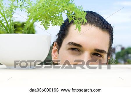 Young man looking closely at potted thyme plant View Large Photo Image Stock Image - Young man looking closely at potted thyme plant. Fotosearch