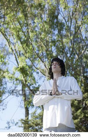Young man meditating outdoors View Large Photo Image Stock Photo - Young man meditating outdoors. Fotosearch