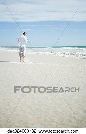 Young man running through surf on beach, rear view View Large Photo Image Stock Image - Young man running through surf on beach, rear view. Fotosearch