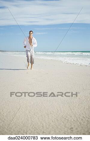 Young man running through surf on beach, front view View Large Photo Image Stock Image - Young man running through surf on beach, front view. Fotosearch
