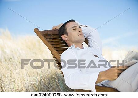 Young man sitting in deck chair, napping View Large Photo Image Stock Photo - Young man sitting in deck chair, napping. Fotosearch