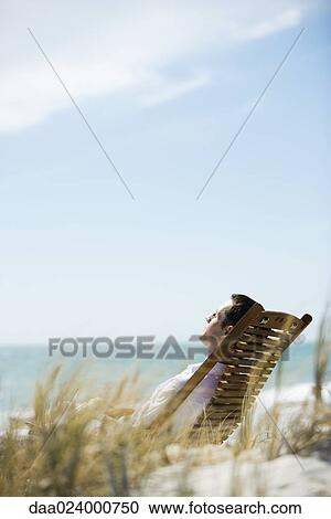 Young man sitting in deck chair View Large Photo Image Stock Image - Young man sitting in deck chair. Fotosearch