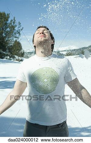 Young man standing in snowy landscape with arms out, head back and eyes closed, under falling snow View Large Photo Image Stock Image - Young man standing in snowy landscape with arms out, head back and eyes closed, under falling snow. Fotosearch
