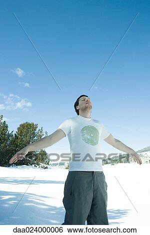 Young man standing in snowy landscape with arms out at sides View Large Photo Image Stock Photograph - Young man standing in snowy landscape with arms out at sides. Fotosearch
