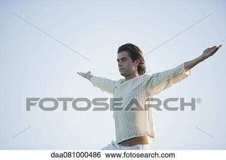 Young man standing with arms outstretched View Large Photo Image Stock Photograph - Young man standing with arms outstretched. Fotosearch