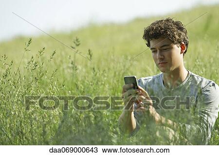 Young man text messaging in nature View Large Photo Image Stock Image - Young man text messaging in nature. Fotosearch
